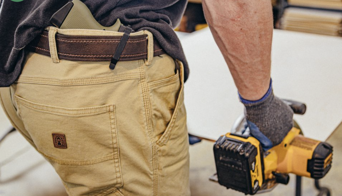 A Clipdraw PSA Micro Dagger belt clip installed on a pistol worn in the waistband of a responsible gun owner cutting plywood with a saw.